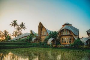 a house in a field with palm trees at Green Lander Ubud in Ubud