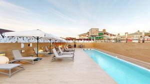 a pool with chairs and umbrellas next to a building at Hotel Andalucía Center in Granada