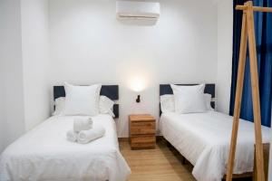 two beds in a room with white sheets and towels at Apartamento Menacho in Badajoz