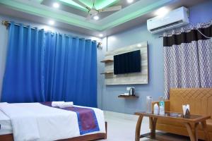 a bedroom with blue curtains and a bed and a tv at S S Plaza in mayapur