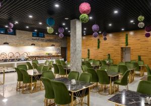 a dining room with green chairs and tables and lights at Lavanda hotel Tashkent in Tashkent