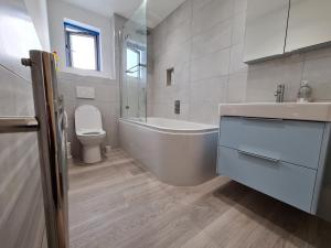 a bathroom with a tub and a toilet and a sink at Double room in a shared 2bed flat in Milton