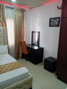 a hotel room with a bed and a desk with a television at Light house hotel lekki phase 1 in Araromi