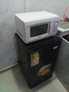 a microwave sitting on top of a black refrigerator at Light house hotel lekki phase 1 in Araromi
