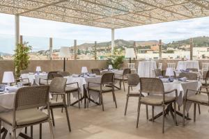 a group of tables and chairs with white tablecloths at Hotel Andalucía Center in Granada