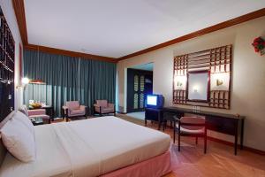 a bedroom with a bed and a desk and a television at Hotel Sahid Toraja in Makale