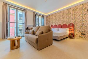 a bedroom with a bed and a couch and a bed and window at Hotel Boutique Porta Ferrisa in Alicante