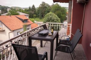 a table and chairs on a balcony with a view at Apartmani ELEGANCE Tuzla in Tuzla