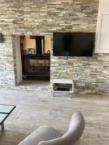 a living room with a television on a brick wall at Sci Licorne d Or in Saint-Méloir-des-Ondes +8 photos