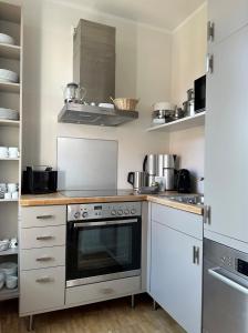 a kitchen with white cabinets and a stove top oven at Rodehuus Wohnung 5 in Borkum
