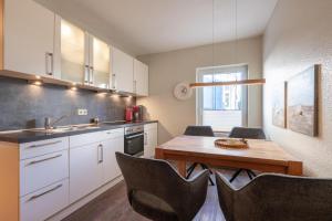 a kitchen with white cabinets and a wooden table at Wittehuus Wohnung 4 in Borkum