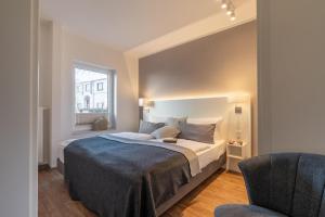 a bedroom with a large bed and a chair at Wittehuus Wohnung 4 in Borkum