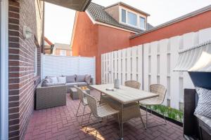 a patio with a table and chairs and a couch at Ferienwohnung Dwarslooper in Borkum