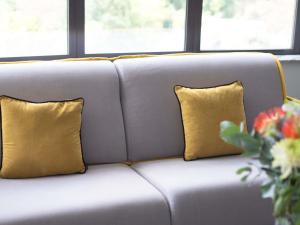 a gray couch with two yellow pillows at Maek Hotel Antwerp Central - Accor Handwritten Collection in Antwerp