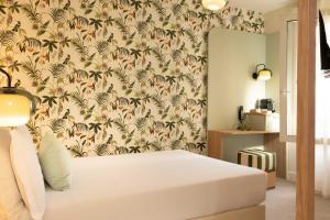 a bedroom with a bed with a wallpaper with palm trees at Hotel La Tonkine ex Olympia in Beausoleil +36 photos