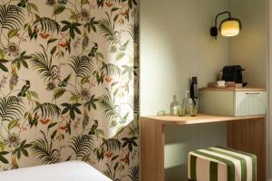 a bedroom with a wall with a floral wallpaper at Hotel La Tonkine ex Olympia in Beausoleil