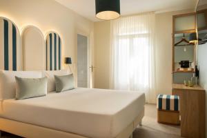 a bedroom with a large white bed and a window at Hotel La Tonkine ex Olympia in Beausoleil