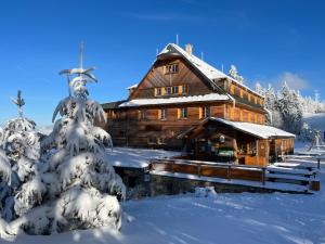 a log cabin in the snow with snow covered trees at Horský hotel Portáš in Nový Hrozenkov