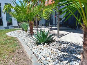 a garden with palm trees and rocks and a sidewalk at Kikapcs apartman in Alsóörs