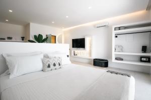 a white bedroom with a white bed and a tv at Lackos Luxury Suites in Imerovigli +128 photos