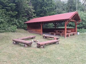 a picnic shelter with wooden benches in a field at Chata LANOVKA - Vojtechova samota in Spišská Nová Ves