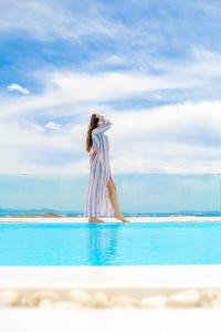 a woman is standing on a surfboard in the ocean at Legendary Suites in Mikonos