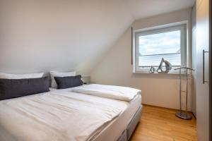 a white bed in a room with a window at Haus Stranddüne in Borkum