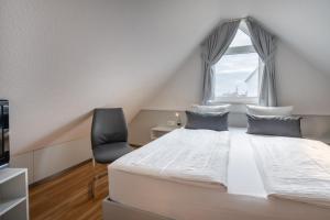 a bedroom with a bed and a chair and a window at Haus Stranddüne in Borkum