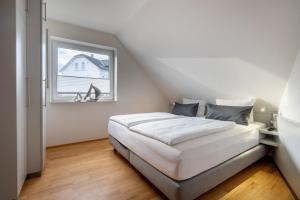a white bedroom with a bed and a window at Haus Stranddüne in Borkum +7 photos