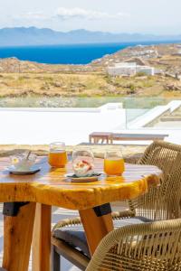 a wooden table with two glasses of orange juice at Legendary Suites in Mikonos