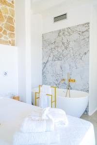 a white bedroom with a bath tub and a bed at Legendary Suites in Mikonos