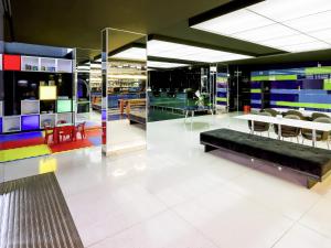 a lobby with a bench and tables and chairs at ibis Styles Confins Aeroporto in Lagoa Santa
