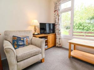 a living room with a chair and a television at Sea Breeze in Bideford