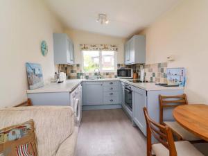 a kitchen with white cabinets and a table and a table at Sea Breeze in Bideford