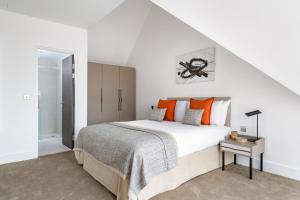a white bedroom with a large bed with orange pillows at Micklegate by Supercity Aparthotels in York