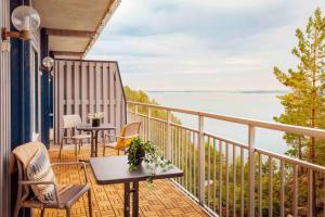 ein Balkon mit Stühlen und Tischen und Blick aufs Wasser in der Unterkunft Vildmarkshotellet in Kolmården