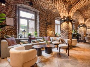 a brick room with a couch and tables and chairs at Blooma Hotel Liege Centre - Accor Handwritten Collection in Liège