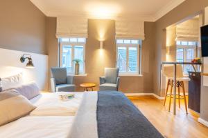 a bedroom with a bed and two chairs and windows at Logierhaus K15 Appartement 10 in Borkum