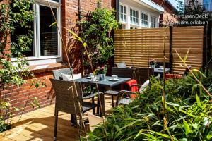 a patio with a table and chairs in a garden at Logierhaus K15 Appartement 10 in Borkum +4 photos