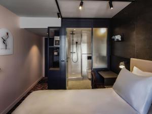 a hotel room with a bed and a shower at TRIBE Paris Batignolles in Paris +97 photos