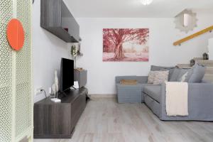 a living room with a blue couch and a tv at Bungalow Sonemar Paradise in Maspalomas
