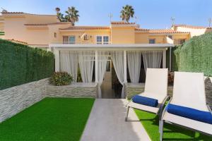 a patio with two chairs and grass at Bungalow Sonemar Paradise in Maspalomas