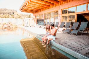 a man and a woman sitting on the edge of a swimming pool at Spa Camping Schwarzwälder Hof in Seelbach