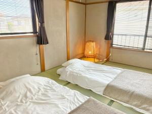 a bedroom with two beds and a lamp in it at さつき邸 -Satsuki House- in Fukuoka