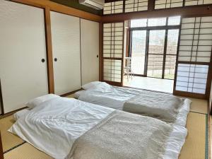 a bedroom with two beds in a room with windows at さつき邸 -Satsuki House- in Fukuoka