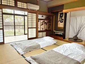 two beds in a room with a window at さつき邸 -Satsuki House- in Fukuoka