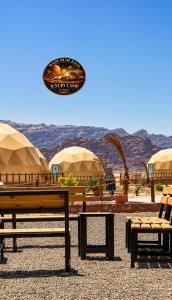 a group of benches and umbrellas with mountains in the background at WADI RUM JULIA lUXURY CAMP in Wadi Rum