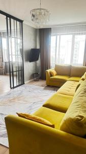 a living room with yellow couches and a chandelier at Алматушечка in Almaty