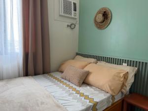a small bedroom with a bed with pillows and a window at 2BR Unit at Hill Residences I Free Parking in Manila +11 photos