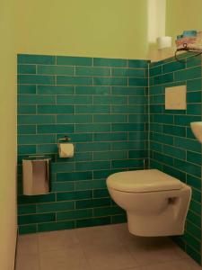 a green tiled bathroom with a toilet and a sink at Das Wilde 70er in Dobritz +17 photos
